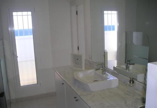 a white bathroom with a sink and a mirror at Nueva Baviera 42 in San Bartolomé