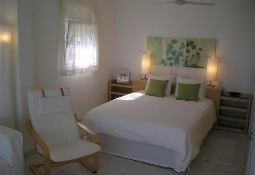 a bedroom with a white bed and a chair at Nueva Baviera 42 in San Bartolomé