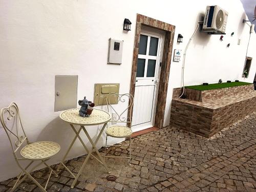 a table and two chairs in front of a door at Casa Gotinha d' Água in Alcaria Ruiva