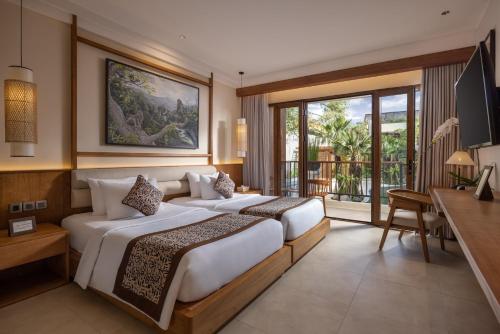 two beds in a hotel room with a balcony at Anumana Ubud Hotel in Ubud