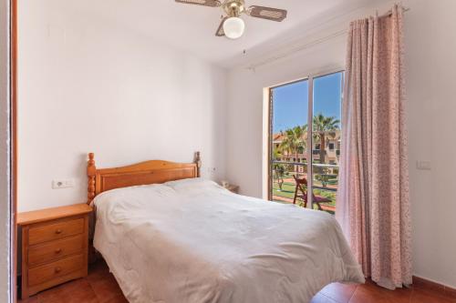 a bedroom with a bed and a window with a view at Duplex Islantilla con piscina in Islantilla