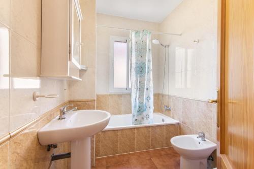 a bathroom with a sink and a toilet and a tub at Duplex Islantilla con piscina in Islantilla