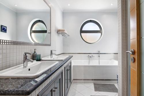 a bathroom with two sinks and a tub and two mirrors at Sunshine Villa em Vilamoura in Vilamoura