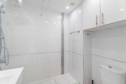 a white bathroom with a shower and a toilet at Castle Harbour in Los Cristianos