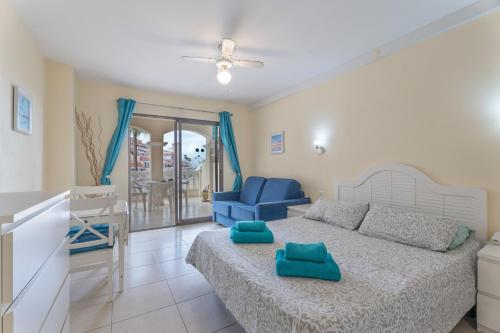 a bedroom with a bed and two blue chairs at Castle Harbour in Los Cristianos