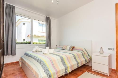a white bedroom with a bed and a window at Villa Elfa in Cala en Forcat