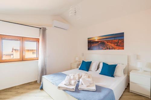 a white bedroom with a bed with towels on it at Villa Elena in Castelsardo