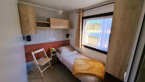 a small room with a bed and a window at Sfeervol Veluws Meerhuisje luxe gezinschalet aan het water met opgemaakte bedden en handdoeken in Nunspeet