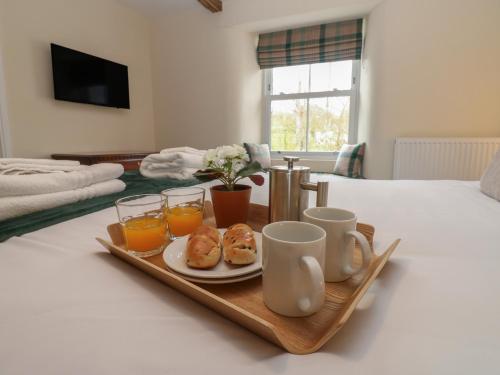 ein Tablett mit Frühstücksspeisen und Getränken auf einem Bett in der Unterkunft 1 Brookside in Warcop