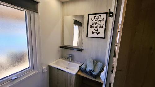 a small bathroom with a sink and a mirror at Sfeervol Veluws Meerhuisje luxe gezinschalet aan het water met opgemaakte bedden en handdoeken in Nunspeet