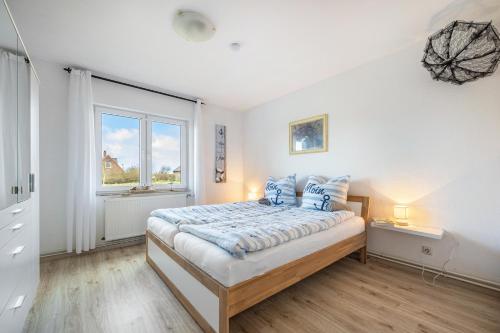 a bedroom with a bed with blue pillows and a window at Ferienhaus Kapitänsstuv in Kaiser Wilhelm Koog