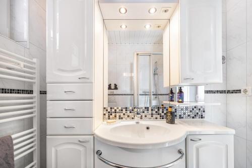 a white bathroom with a sink and a mirror at Ferienhaus Kapitänsstuv in Kaiser Wilhelm Koog