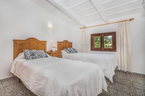 a white bedroom with two beds and a window at Sontuiri den Jaume in Pollença