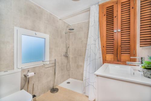 a bathroom with a sink and a shower with a window at Sontuiri den Jaume in Pollença