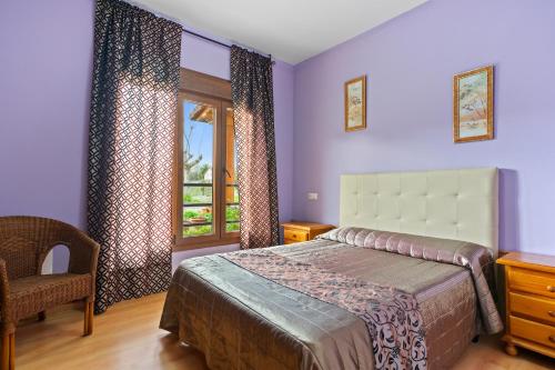 a bedroom with a bed and a chair and a window at Apartamentos Les Cuartes in Cangas de Onís