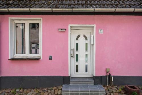 a pink house with a white door and windows at Wanderpfoten Ostsee Ferienhaus in Tribsees