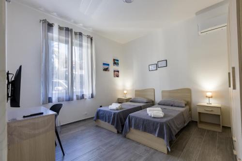 a hotel room with two beds and a television at Casa Gioiosa Holidays in Gioiosa Marea
