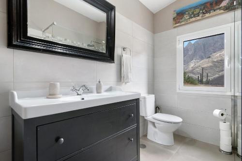 a bathroom with a sink and a toilet and a mirror at Los Jazmines in Agaete