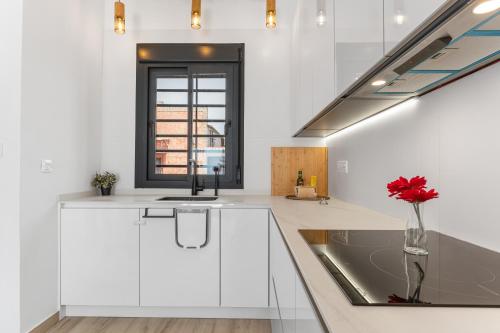 a kitchen with white cabinets and a vase with a red flower at Casa Catral Alfalfar 12 in Catral