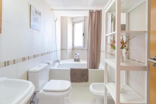 a white bathroom with a toilet and a bath tub at Vivienda maiva in Alhama de Murcia