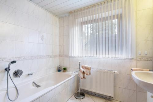 a white bathroom with a tub and a sink at Ferienwohnung Tannenberg in Diemelstadt 
