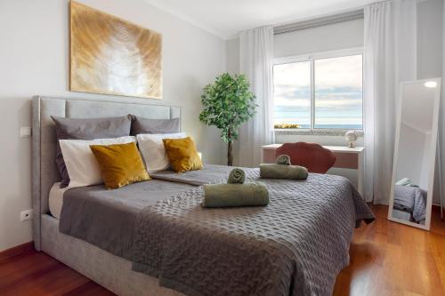 a bedroom with a bed with yellow pillows and a window at Ti Clara View Apartment in Caniço