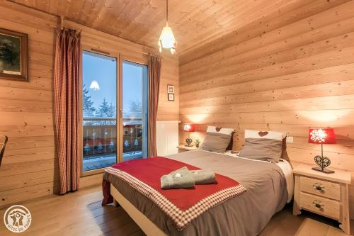 a bedroom with a bed and a large window at Gîte Au Pré De La Basse in Orcier