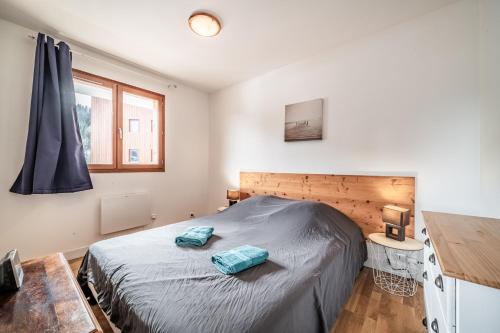 a bedroom with a bed with two blue pillows on it at Appart 6 pers – Accès direct Ski in Morillon