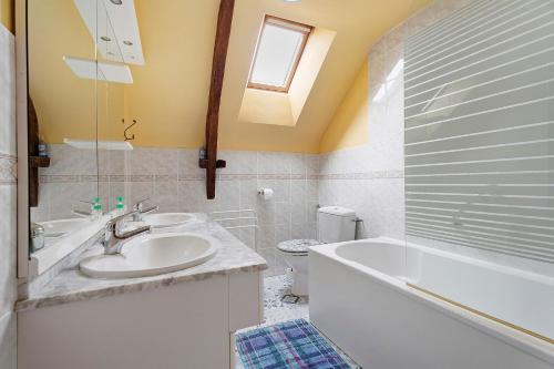 a bathroom with a sink and a tub and a toilet at Gite Hirondelle in Lanvallay