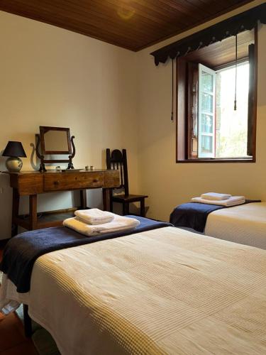 a bedroom with two beds and a desk and a window at Casa Da Azenha in Baião