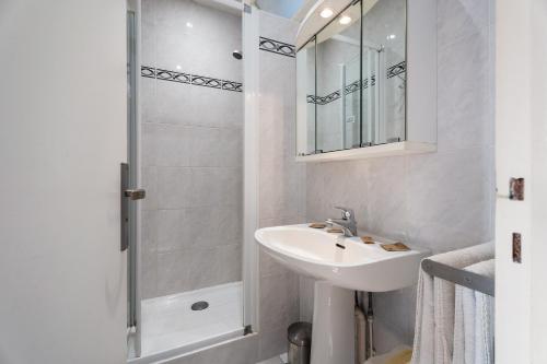a white bathroom with a sink and a shower at La Mansardière in Cancale