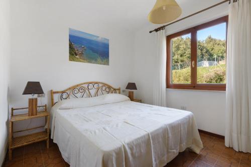 a white bedroom with a bed and a window at Hause Sant'Ilario in Campo nell'Elba