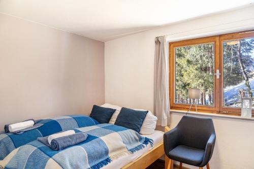 a bedroom with a bed and a chair and a window at Sonnenhütte Wildschönau Erdgeschoß in Grafenweg