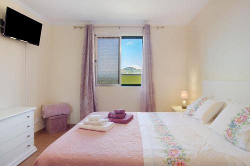 a bedroom with a large white bed with a window at Levada Residence in Funchal
