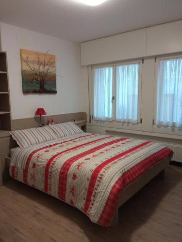 a bedroom with a bed with a red and white blanket at La Casetta Gialla in Pieve di Cadore