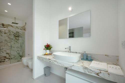 a white bathroom with a sink and a mirror at Villa Nilde in Triggianello