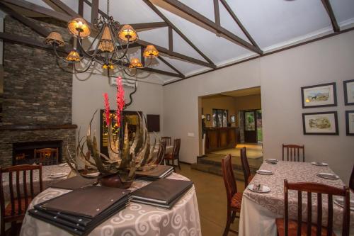 a dining room with a table and a chandelier at Hamiltons Lodge & Restaurant in Malelane
