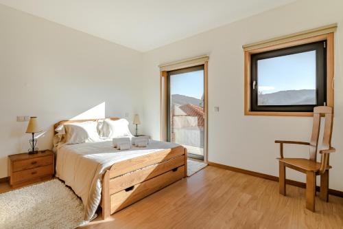 a bedroom with a bed and a window and a chair at Casa Feixa Gerês in Geres