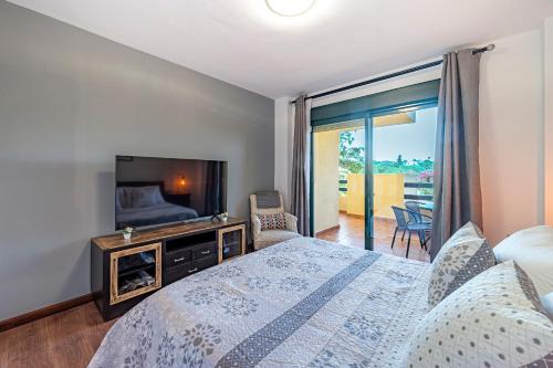 a bedroom with a bed and a tv and a balcony at Apartamento Las Joyas in Estepona