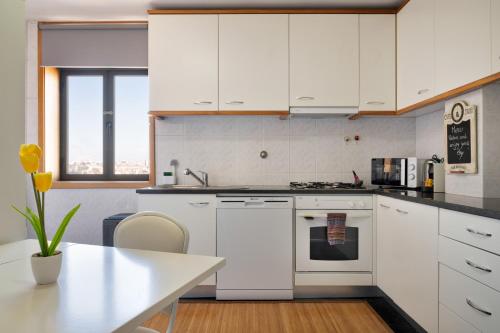 a kitchen with white cabinets and a white table at Wander Unwind - Wine Cellars in Vila Nova de Gaia