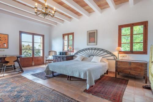 a bedroom with a bed and a desk and windows at Casa Roca Esporles in Esporlas