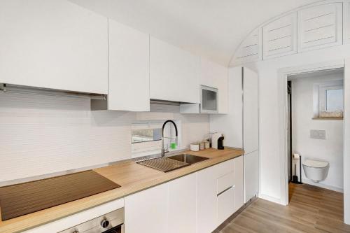 a white kitchen with white cabinets and a sink at Casa Quattrocchi in Barano d'Ischia