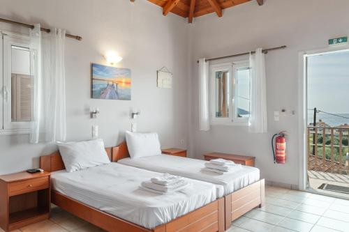 a bedroom with a bed with white sheets and a window at Chroma Finikounda 2 in Finikounta