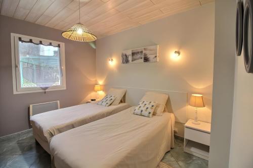 two beds in a small room with a window at Gîte Pors Mabo in Trébeurden