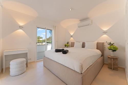 a white bedroom with a large bed and a window at Casa Baskings in Portopetro