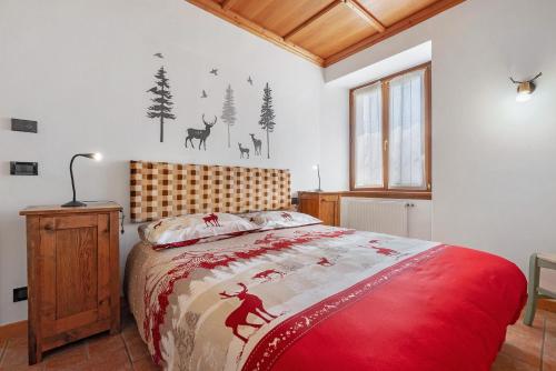 a bedroom with a bed with a red comforter at Appartamento Ca' Mocc in Porte di Rendena