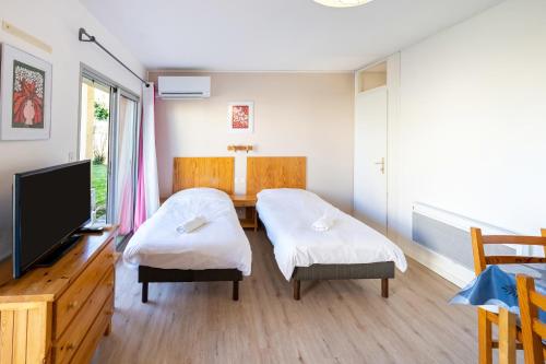 a room with two twin beds and a television at Les Mimosas - Appartement 06 in Cazaubon