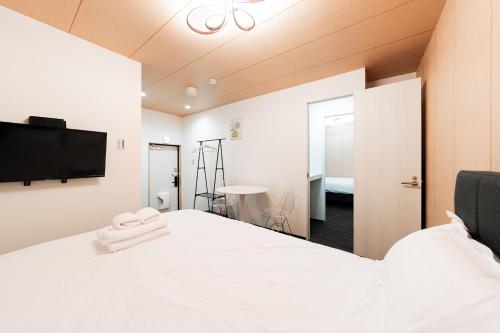a bedroom with a white bed with a tv on the wall at GLOU Akasaka Inn in Tokyo