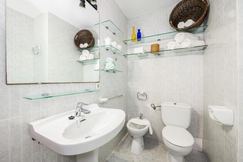 a white bathroom with a toilet and a sink at Villa Lucia in Portocolom