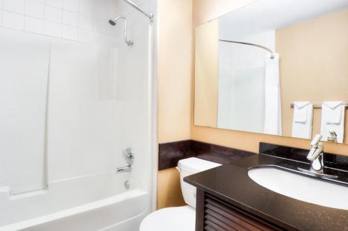 a bathroom with a sink and a toilet and a mirror at Travelodge by Wyndham Miramichi New Brunswick in Miramichi